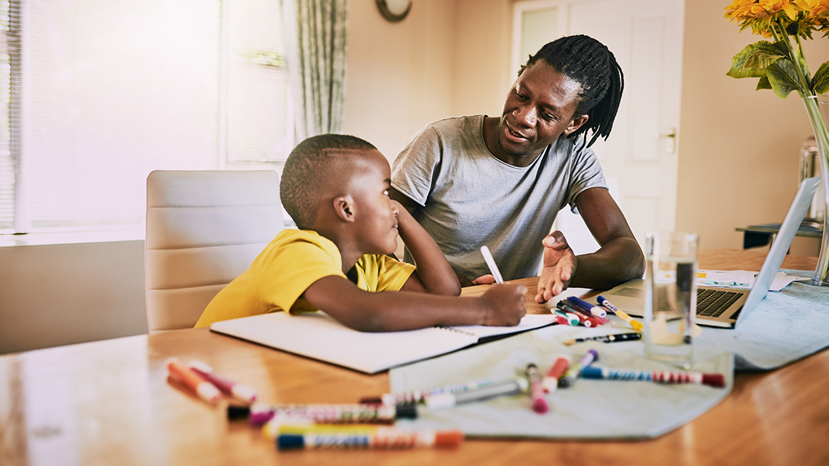 affectionate young single father helping his son with his homework at home