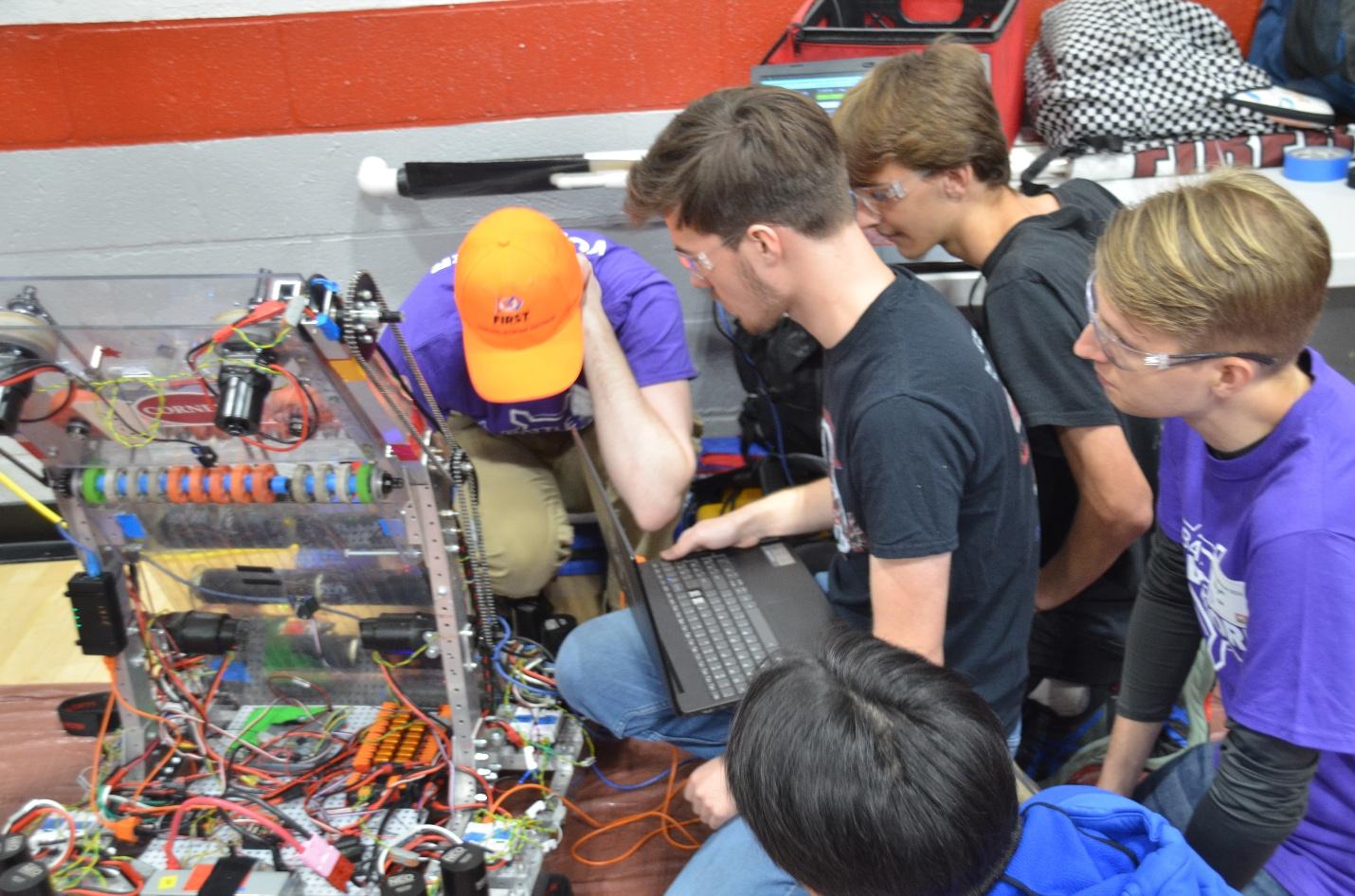 Robotic team troubleshoots a software problem with support from fellow students.
